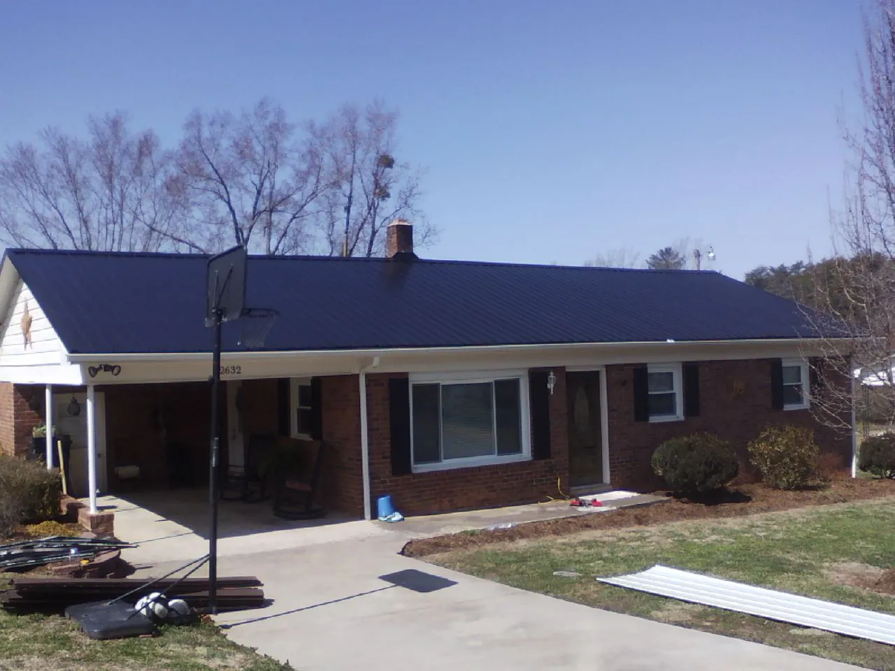 Finished dark blue metal roof on a brick ranch with a carport in Batesville