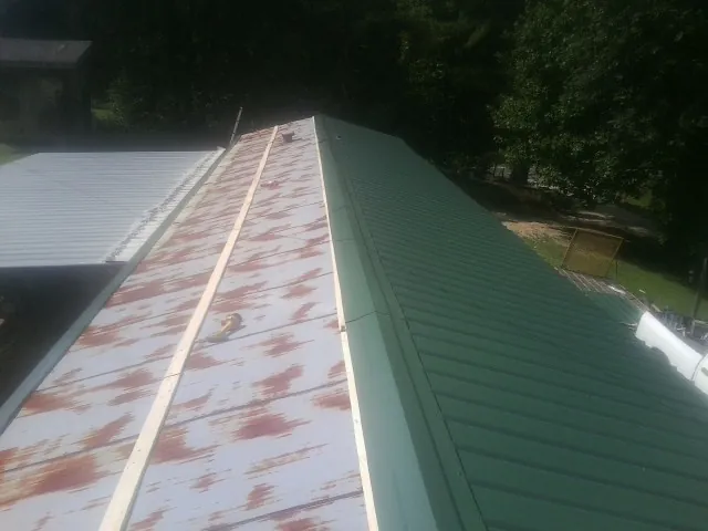 Old rusted panels beside newly installed green metal roofing — Wind Damage Roof Repair by Roofing Brothers in Batesville