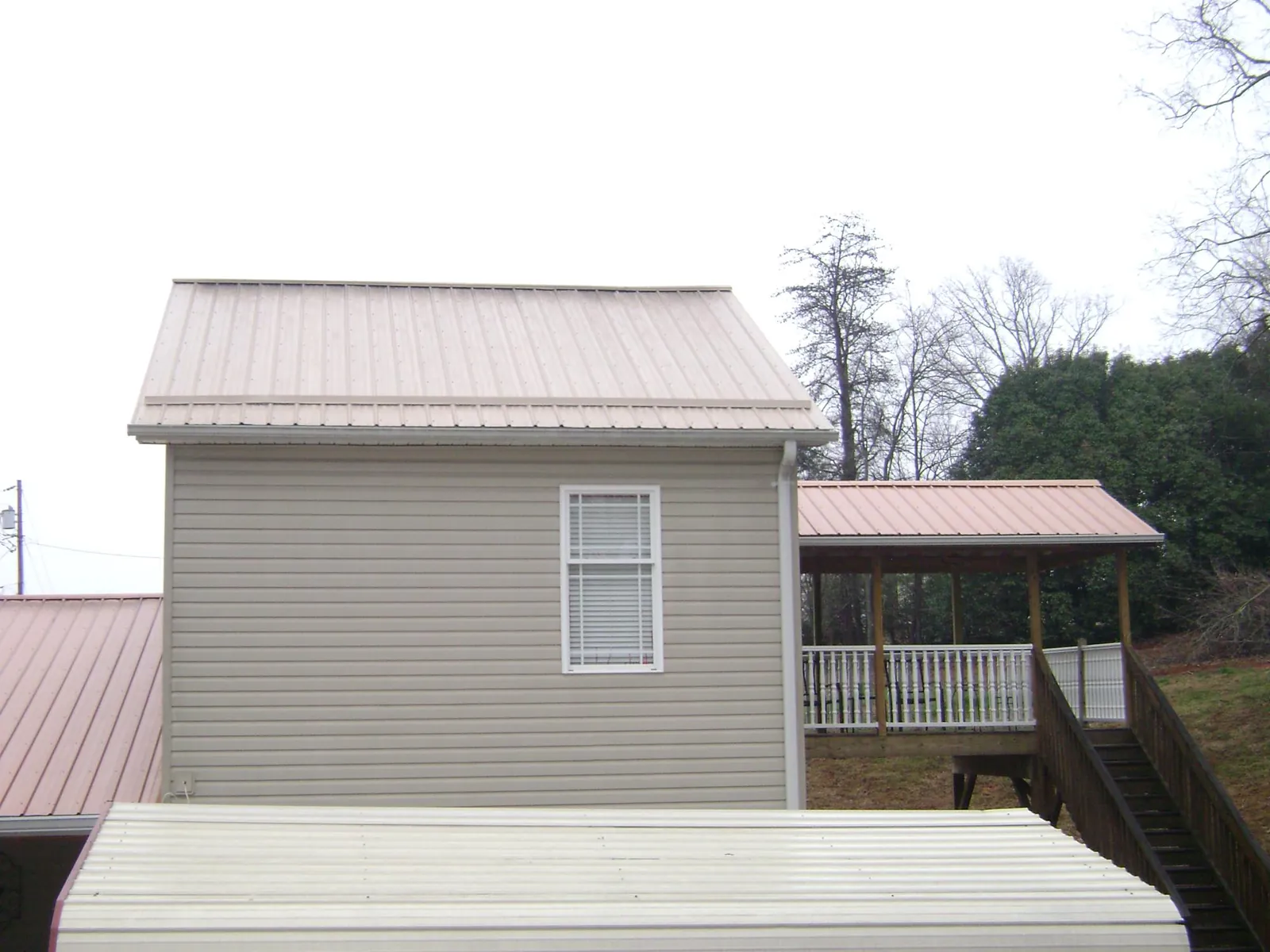 Tan metal roofs on a two story addition and attached porch, from a Roof Replacement job in Batesville